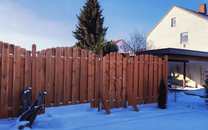 Board-on-board wood privacy fence in a backyard with snow on the ground