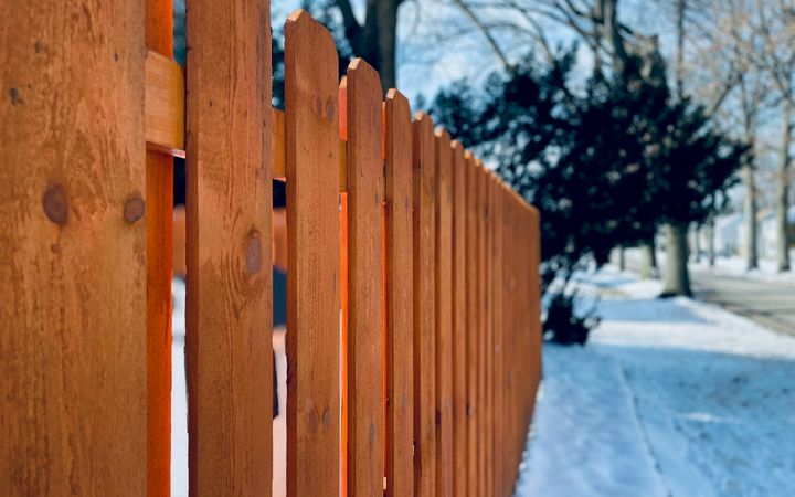 Cedar board fence beside a snowy sidewalk